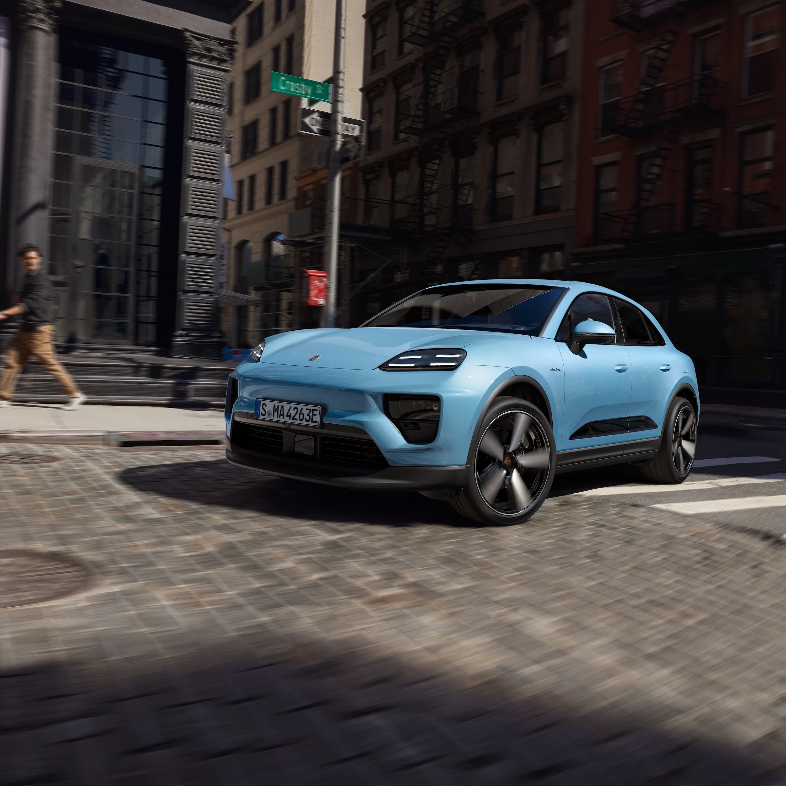Une Porsche Macan 100% électrique circulant sur une route dans un scénario urbain.